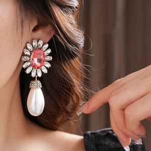 Détail d'une boucle d'oreille fleurie avec cristal rouge et perle sur un mannequin