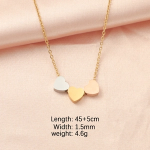 Detailed view of three-color heart pendants in silver, gold, and rose gold on pink silk