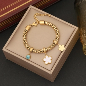 Detailed view of a gold beaded bracelet with flower charms and turquoise on leather