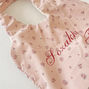 Detail shot of the delicate red floral print on the light pink baby bib fabric