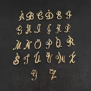Vue macro de breloques alphabet en acier inoxydable or 18 carats au style cursif