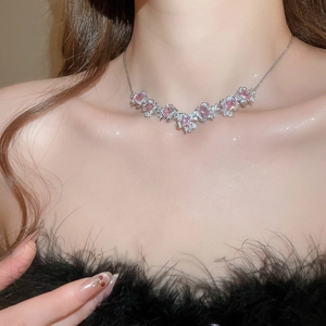 Close-up of a silver necklace with a pink square zircon flower pendant on a female model