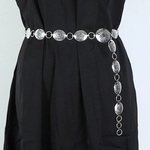 Detail of silver chain belt featuring engraved sunflower metal discs on a black dress
