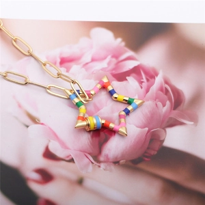 Close-up of golden necklace with colorful enamel star pendant and zircon twist buckle
