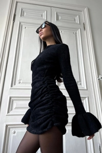 Détail des manches évasées et des fronces sur une robe courte en maille noire chic