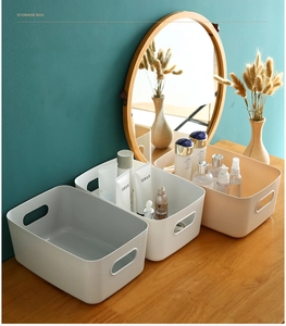 Detailed view of matte plastic storage boxes with cutout handles on a vanity desk
