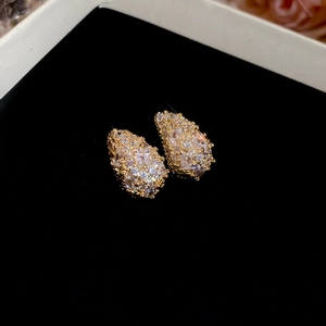 Detailed macro view of pear-shaped gold earrings with white cubic zirconia micro-paving