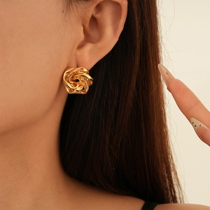 Close-up of a model wearing the golden metal flower earring with a layered twisted rose design
