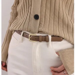 Brown slim leather belt with gold pin buckle styled on white jeans and a cardigan