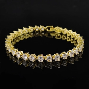 Detailed close-up of a gold-plated tennis bracelet with round cubic zirconia on black mirror