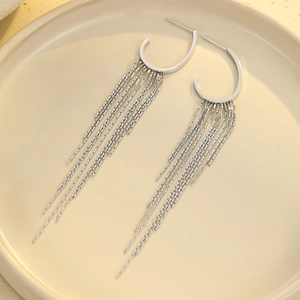 Close-up of silver tassel earrings with C-shaped hoops and delicate metal chains on a tray