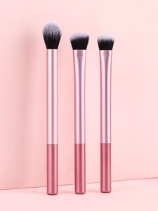 Trois pinceaux de maquillage avec manches métalliques roses et poils ombrés noir et blanc