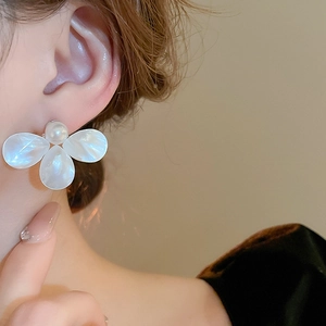 Close-up of elegant flower stud earrings with pearl center and mother-of-pearl petals