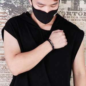 Close-up of black double-layered braided leather bracelet on wrist against street wall