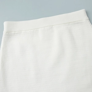 Detail of white knit skirt with elastic ribbed waistband and horizontal ribbed texture