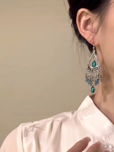 Close-up of ethnic style teardrop earrings with turquoise beads and silver tassels