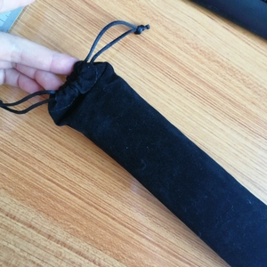 Detail of a premium black velvet drawstring pouch for fan storage on a wooden table