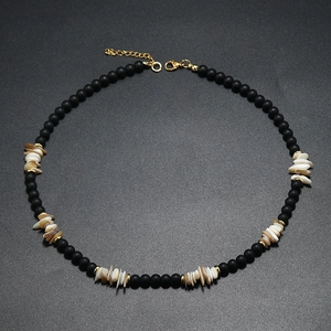 Gros plan détaillé du collier bohème avec perles noires mates et fragments de coquillages