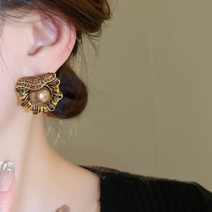 Gros plan d'une boucle d'oreille vintage en forme d'éventail avec perle et strass marron