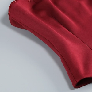 Détail d'une robe de soirée rouge foncé avec broderies de perles et tissu de qualité