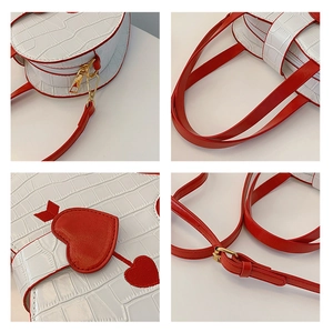 Detail of white crocodile pattern bag featuring red heart design and gold metal zippers