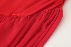 Close-up of red plain fabric stitched with matching mesh panels on a stylish dress