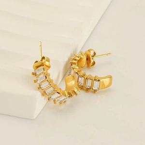 Minimalist gold U-shaped hoop earrings with baguette-cut zircons on a white display