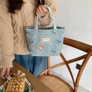 Détail du sac en toile bleu ciel avec broderie papillon et étiquette en tissu cousue