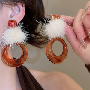 Dettaglio di orecchini vintage in resina arancione marmorizzata con pompon bianco