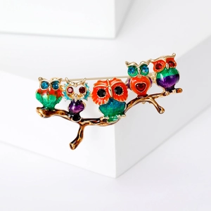 Close-up of five colorful enamel owls on a golden branch brooch with vivid details