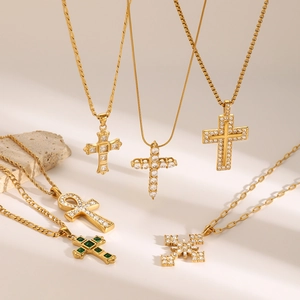 Close-up of six gold-plated stainless steel cross necklaces with zircon inlays on a stone base