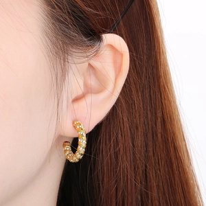 Macro shot of 18K gold plated C-shape hoop earrings with spiral diamond inlay on model