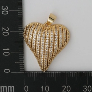 Macro detail of gold striped heart pendant with zircon inlay and measurement scale