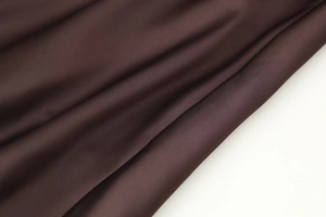 Close-up of chocolate brown satin dress fabric showing luxurious silky texture and drapes