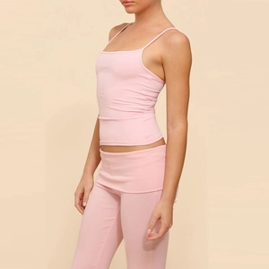 Dettaglio del top rosa a spalline sottili e pantaloni svasati da yoga a vita alta