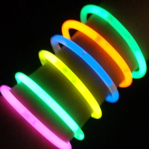 Gros plan de bâtons lumineux multicolores portés en bracelets lors d'un concert