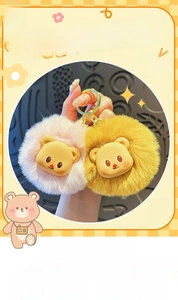Detail of cute plush cream bear keychains in pink and yellow with golden metal hardware