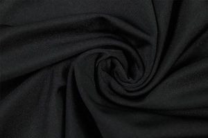 Macro shot of high-quality black knitted fabric texture with elegant pleated swirls