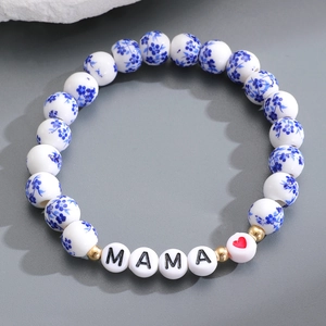 Dettaglio del bracciale con perline di ceramica blu e bianche e ciondolo MAMA dorato