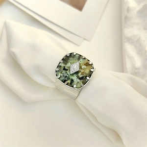Detail of vintage square turquoise ring on white fabric showing green stone and silver band