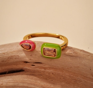Macro view of gold open ring with pink teardrop and green rectangle enamel and gems