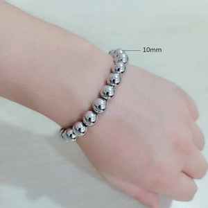 Detail of a 10mm silver steel bead bracelet worn on wrist over a wooden background