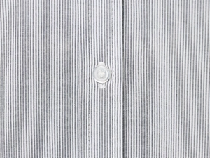 Macro shot of vertical pinstripe fabric and white button detail on the shirt