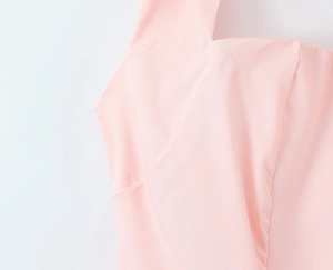 Dettaglio dello scollo dell'abito rosa con focus su cuciture e trama del tessuto fine