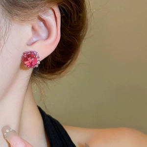 Close-up of elegant pink crystal stud earrings worn by a model in natural lighting