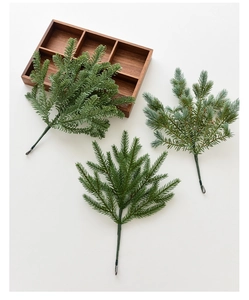 Detailed close-up of three artificial pine branches in various green shades on white backdrop