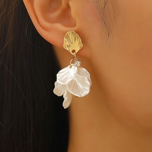 Gros plan de boucles d'oreilles coquillage doré avec pétales blancs sur mannequin