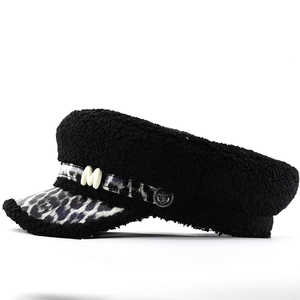Détail de la casquette gavroche en laine bouclée noire avec visière léopard et pendentif