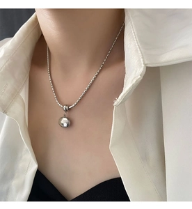 Close-up of minimalist silver bead pendant necklace on square chain for women