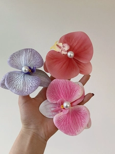 Detail of fabric orchid hair clips with center pearl in purple, red and pink colors